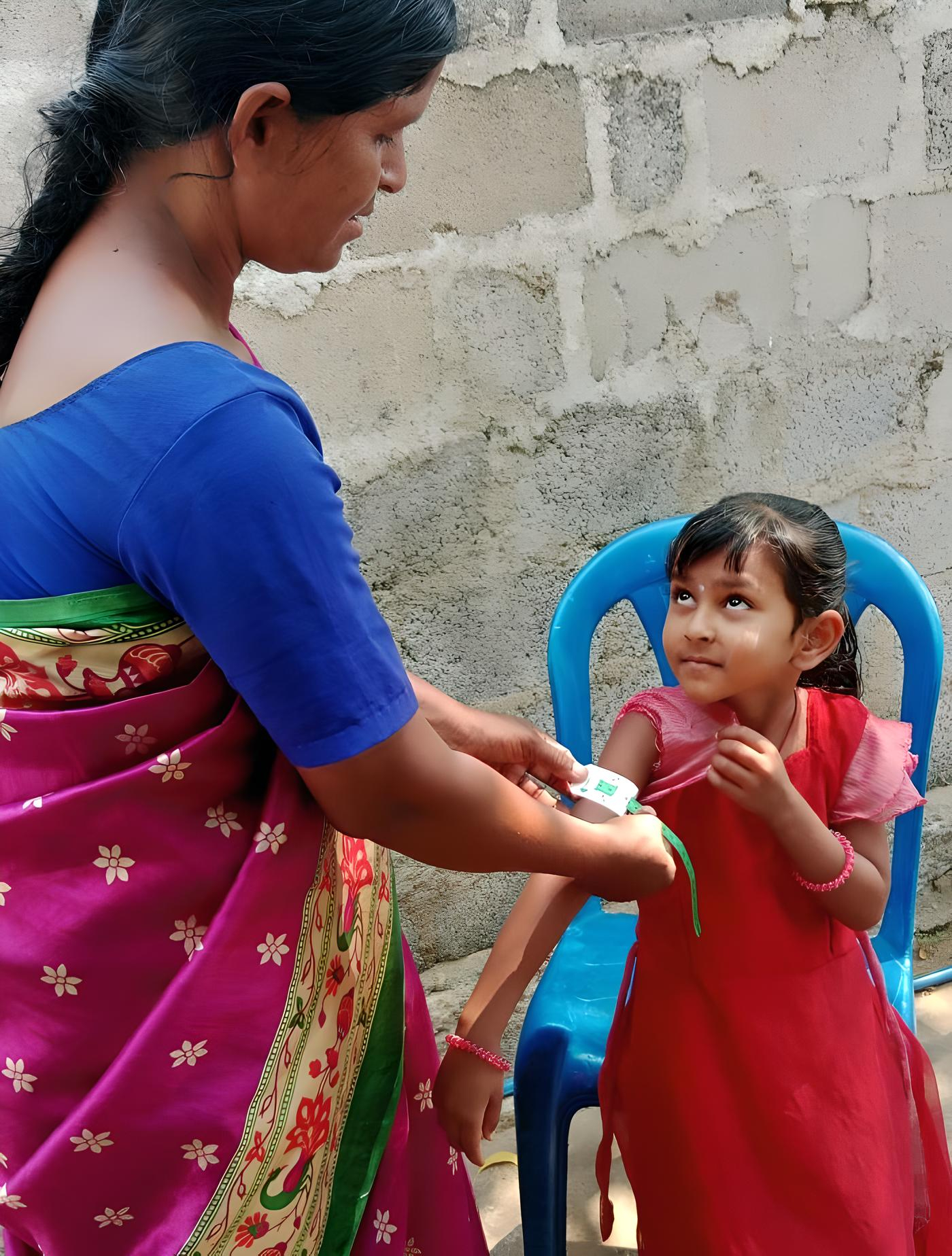 Ruthamma using a MUAC tape to check for proper growth.